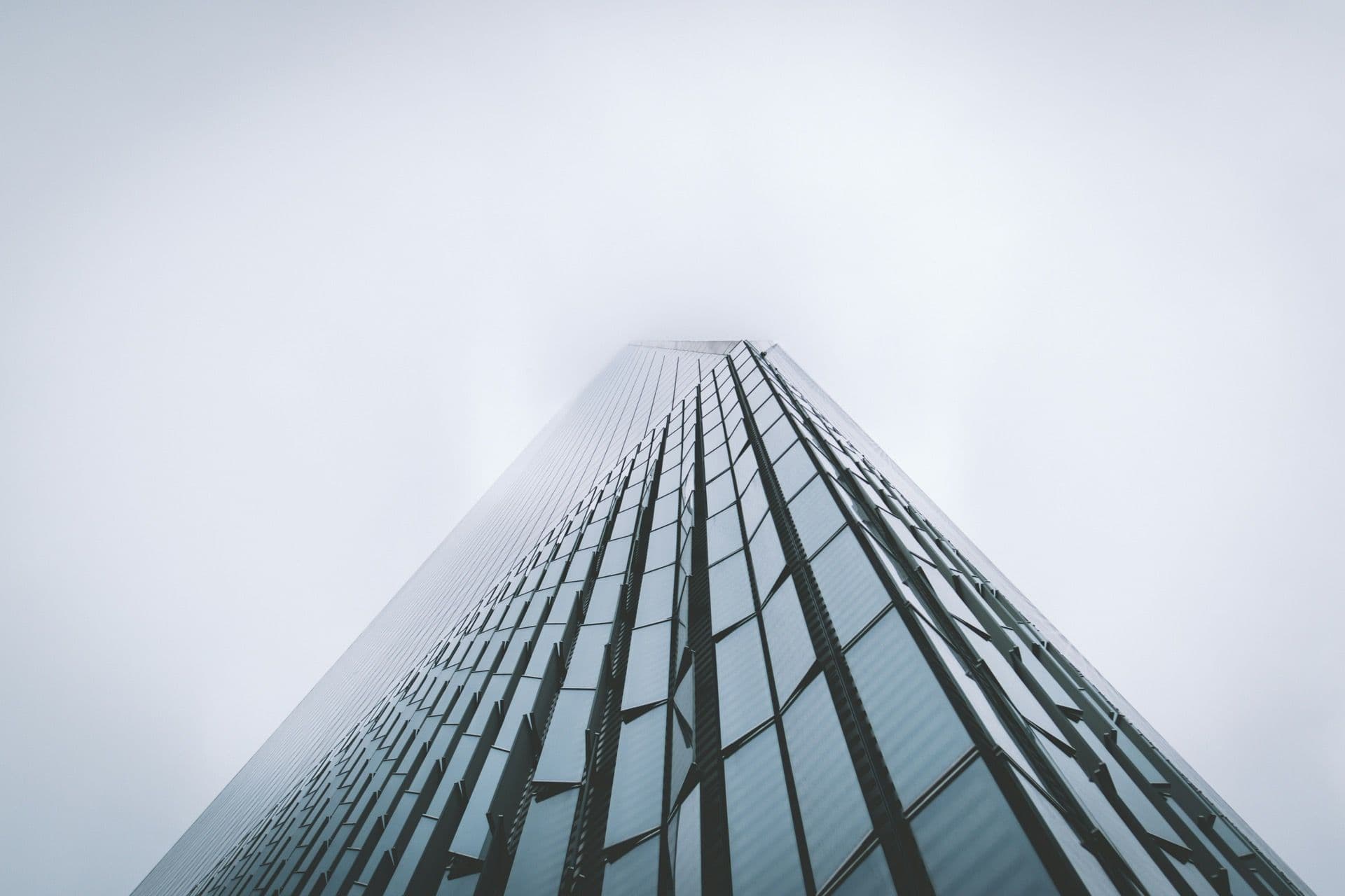 Glass skyscraper rising into fog